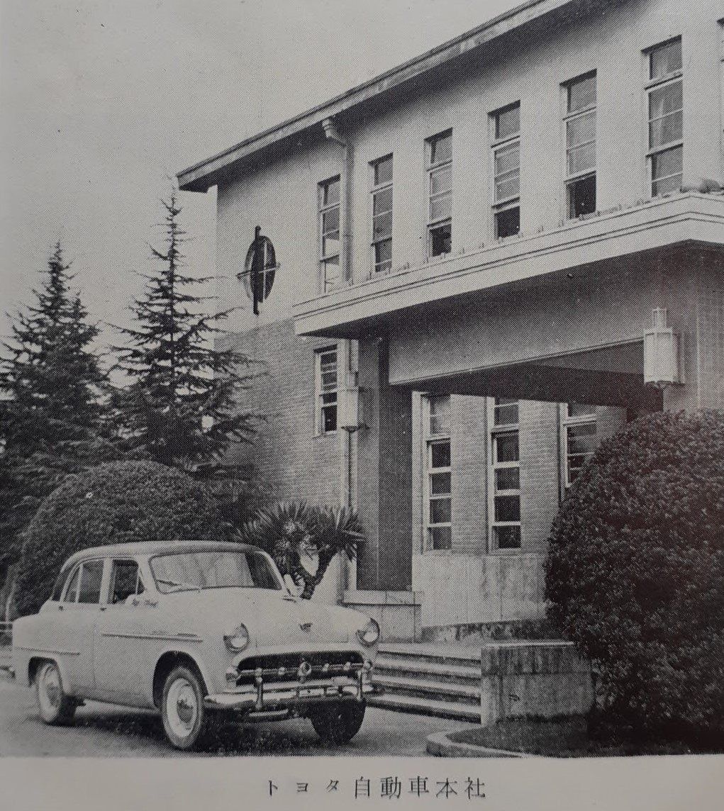 Black-and-white photo of Toyota's head office with a 1950s car in front