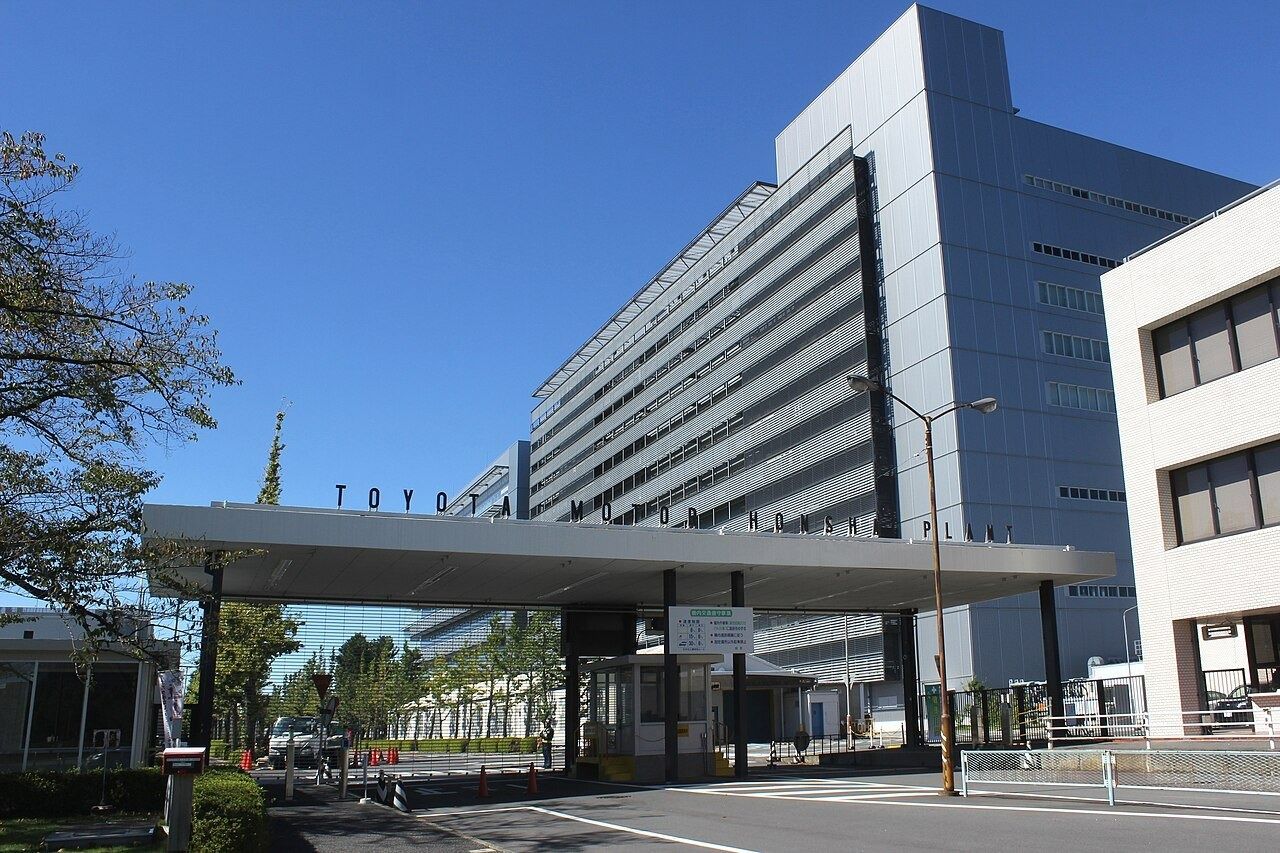 Large white plant building behind a Toyota gate