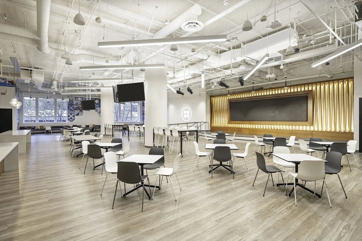 Twilio: Open café area with white tables and a lit timber wall
