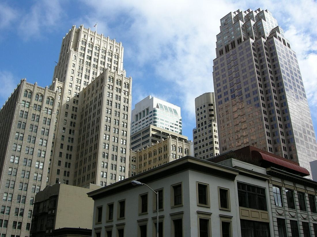 Downtown skyscrapers rising behind an older low building under a blue sky
