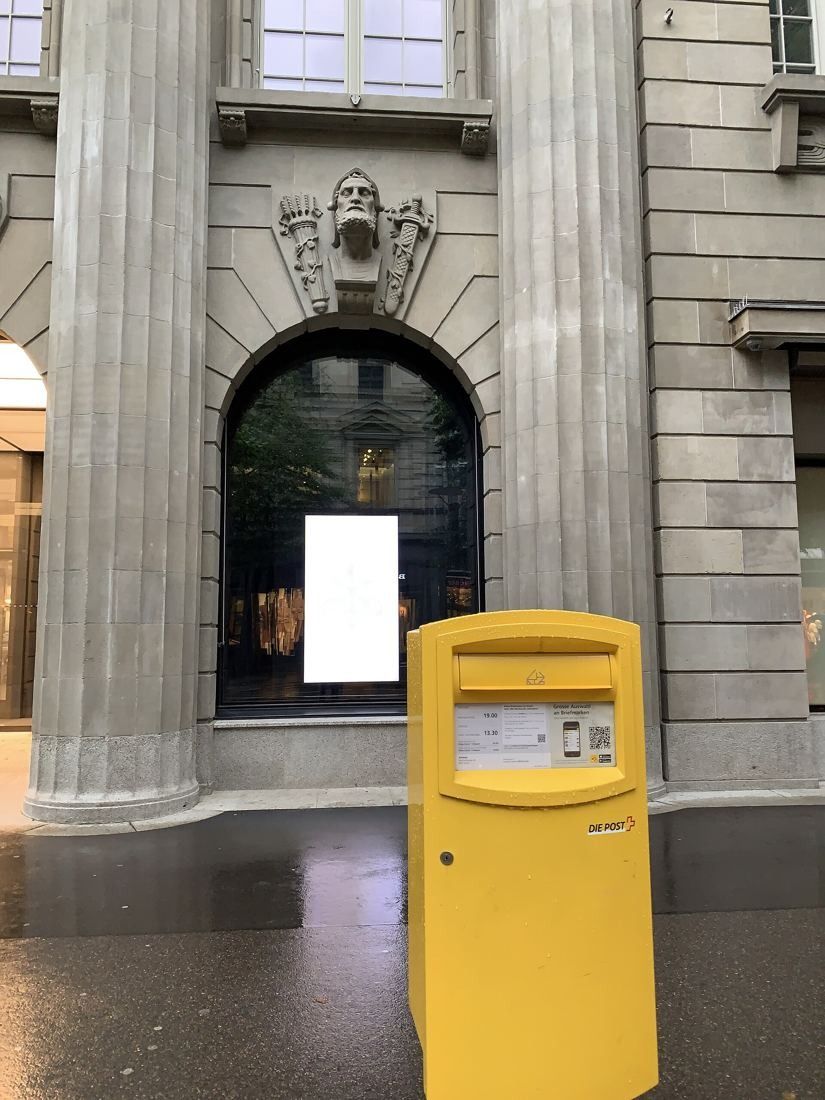 UBS: Arched window between columns with a yellow postbox in the foreground