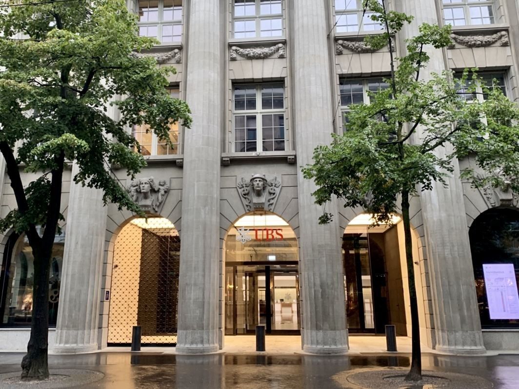 UBS: Columns and arched ground-floor openings with lit interiors behind street trees