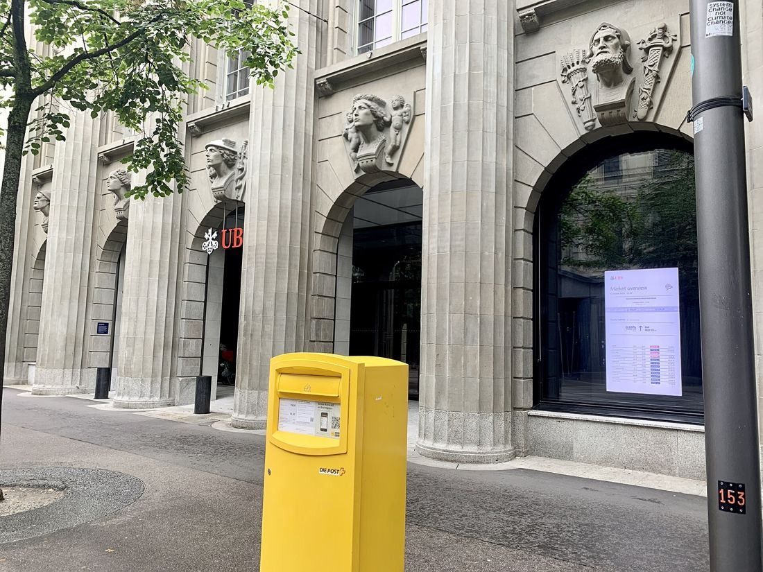 UBS: Columns with carved heads and an arched entrance, a yellow postbox in front