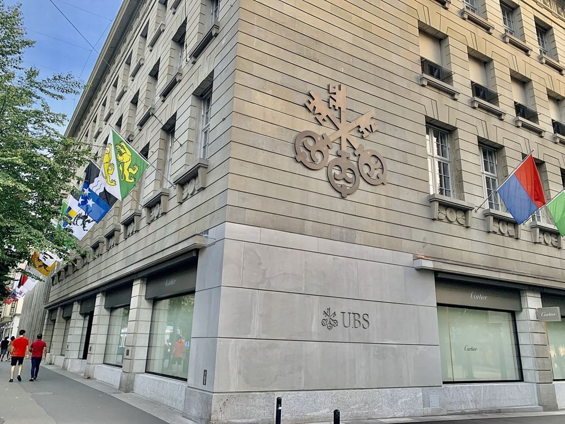 UBS: Stone corner with a three-key relief and flags along the side street