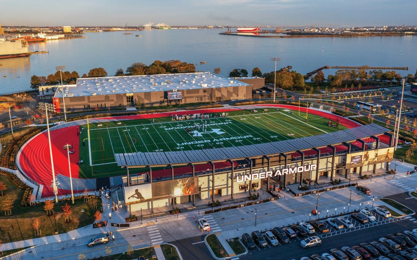 Under Armour: Aerial view of the stadium with red track, football field and covered stand beside the water
