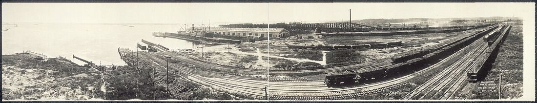 Wide old panorama of rail yards, piers and warehouses on the harbour shore