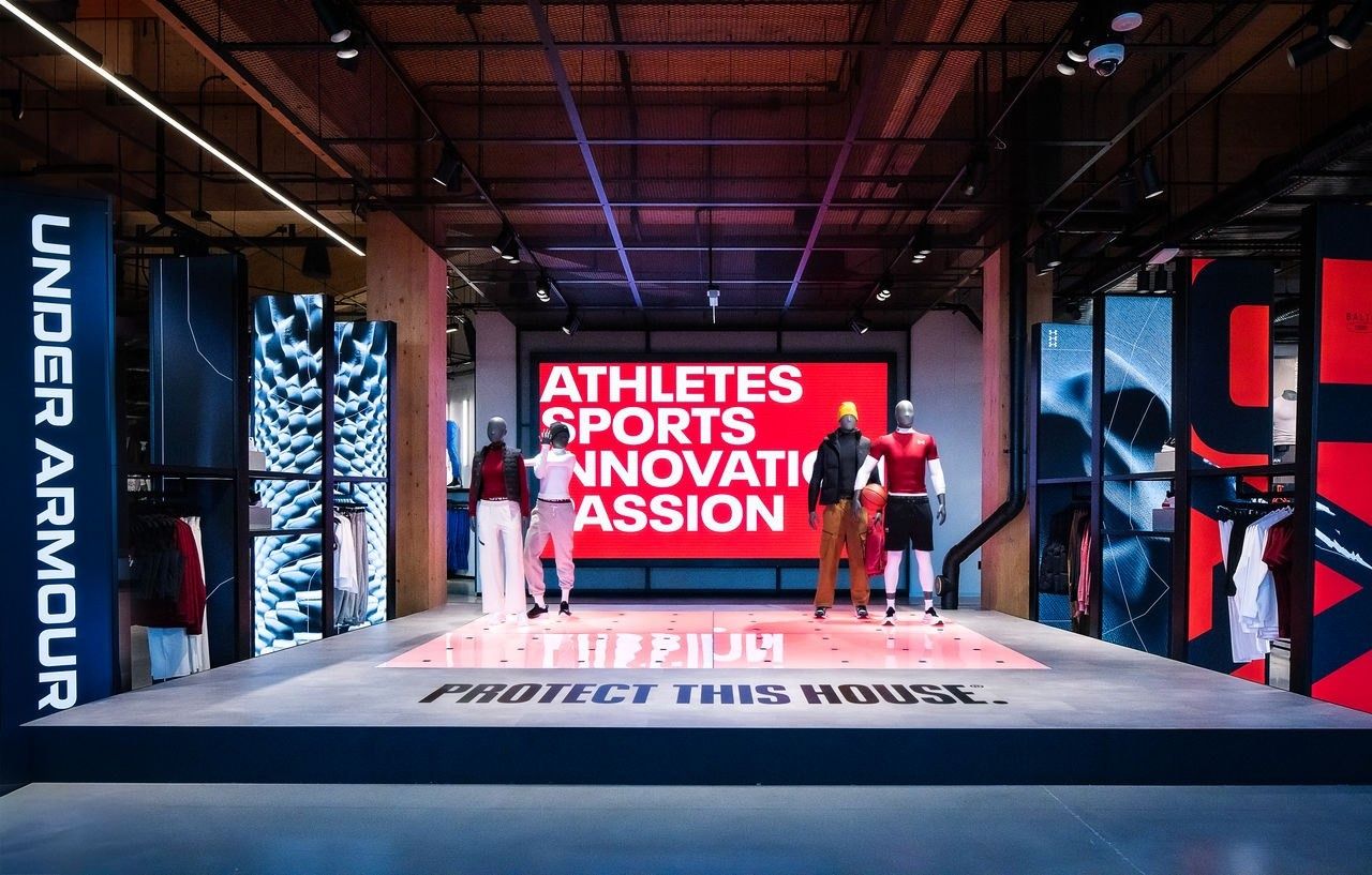 Under Armour: Stage with mannequins and a large red screen, Protect This House written on the floor