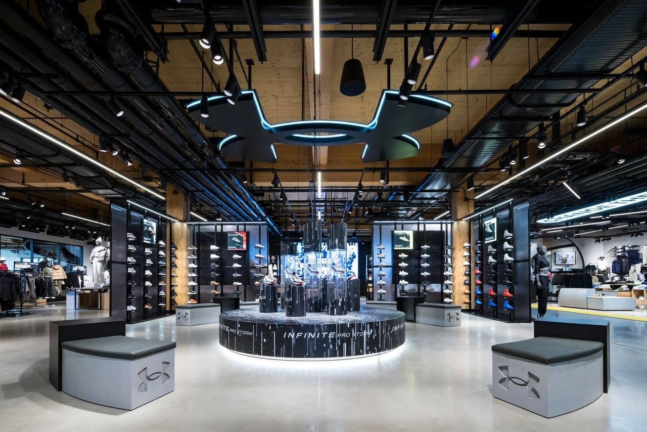 Under Armour: Store interior with wooden ceiling, black display towers and a round illuminated centre display
