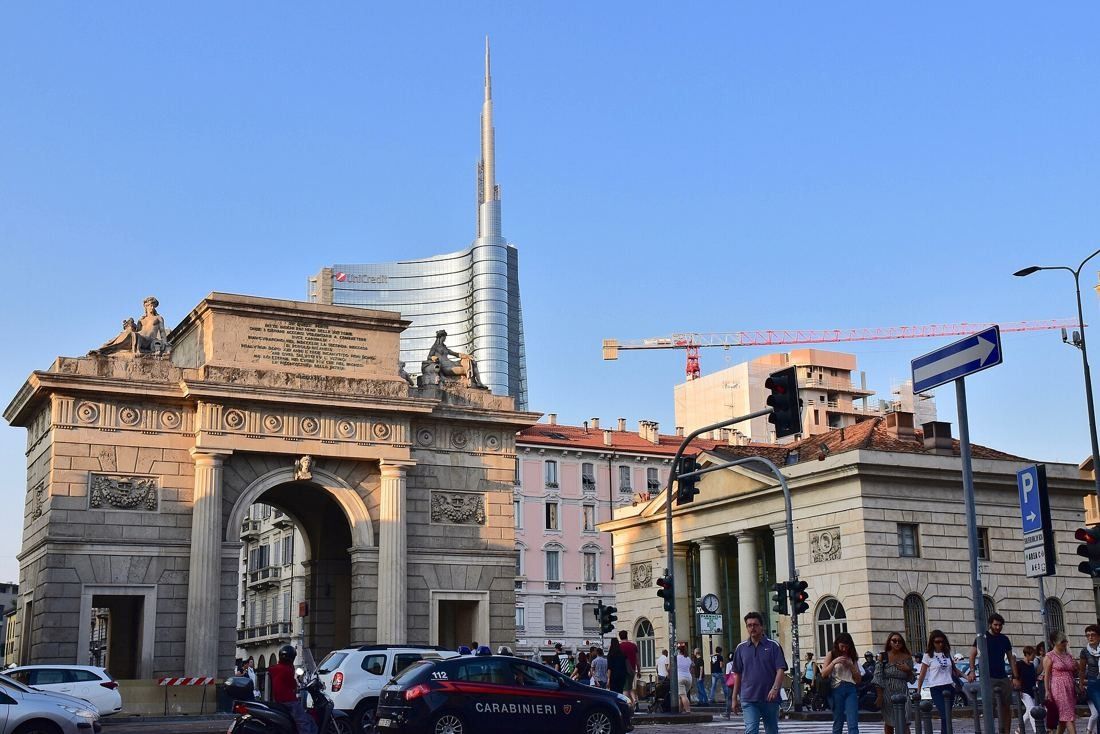 UniCredit: Neoclassical city gate with the spired glass tower rising behind it