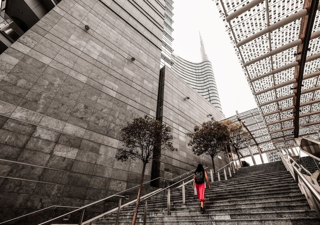 UniCredit: Stone stairway beside a dark stone wall, with the glass tower and spire behind