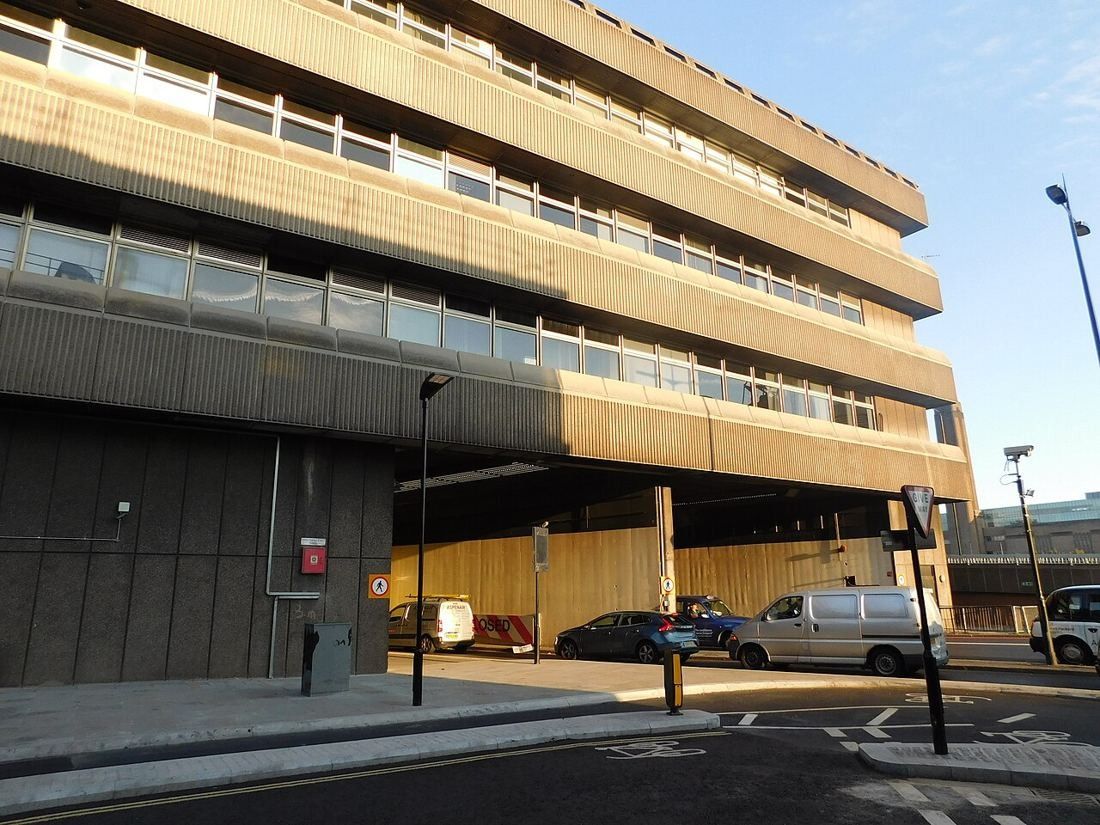 City street lined with a modern concrete office block and an overpass
