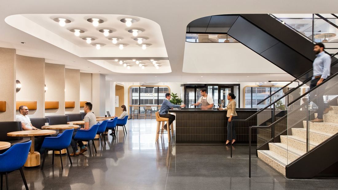 United Airlines: Café counter and seating under a ceiling of round lights, with a black steel stair on the right
