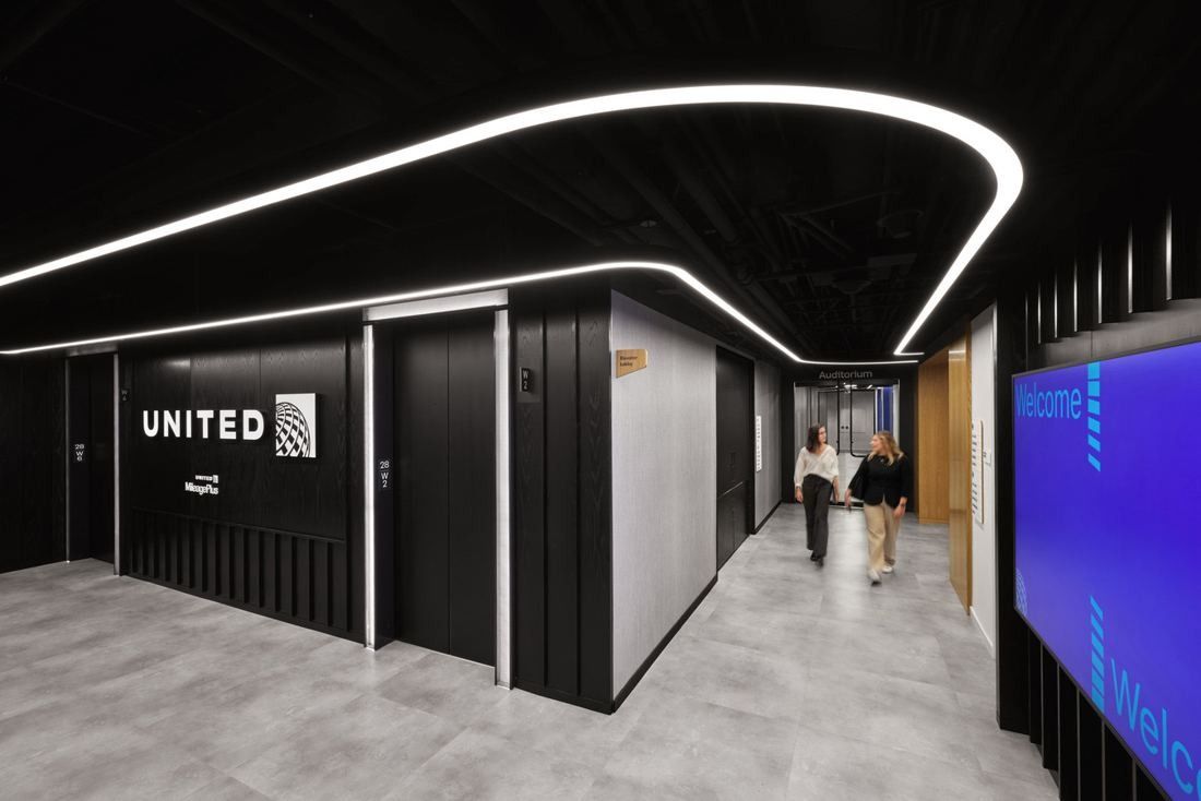 United Airlines: Dark elevator lobby with a curving line of light on the ceiling and a blue screen wall