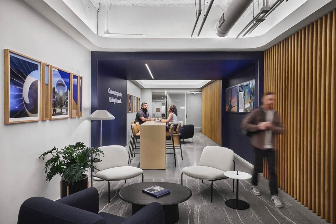 United Airlines: Small lounge with white chairs, a round table and framed pictures on wood-slatted walls
