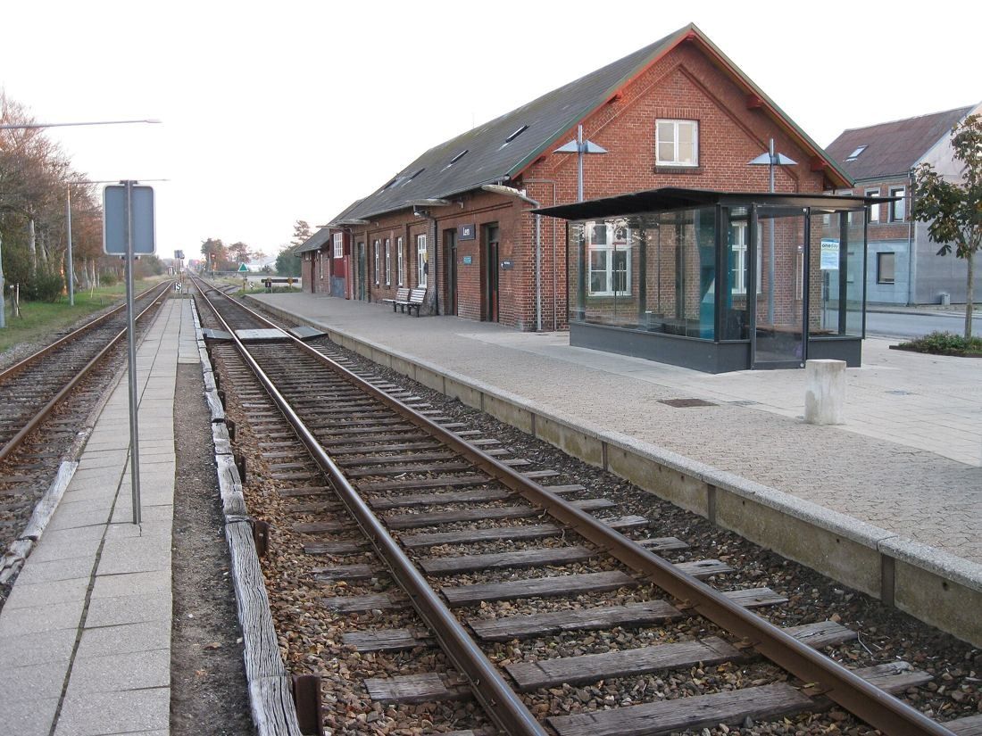 Red-brick station building beside a single railway track and platform