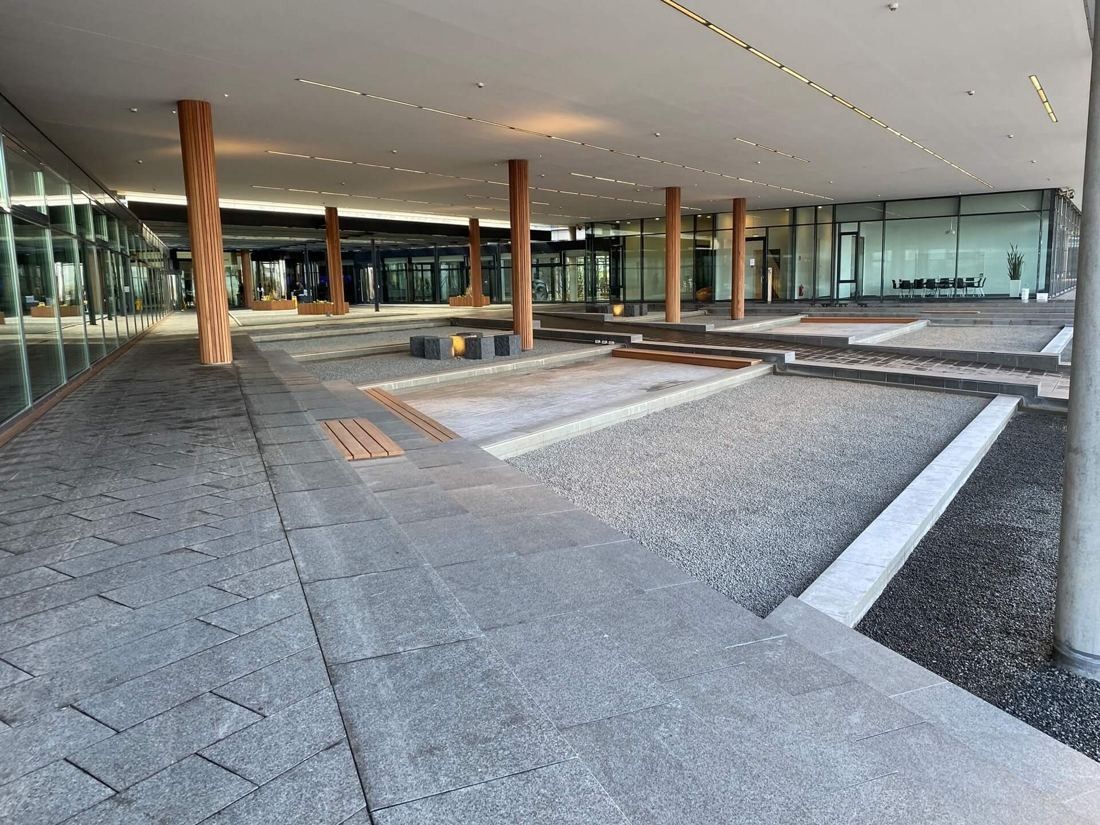 Vestas: Stone-paved forecourt under a canopy with wooden columns and low gravel beds