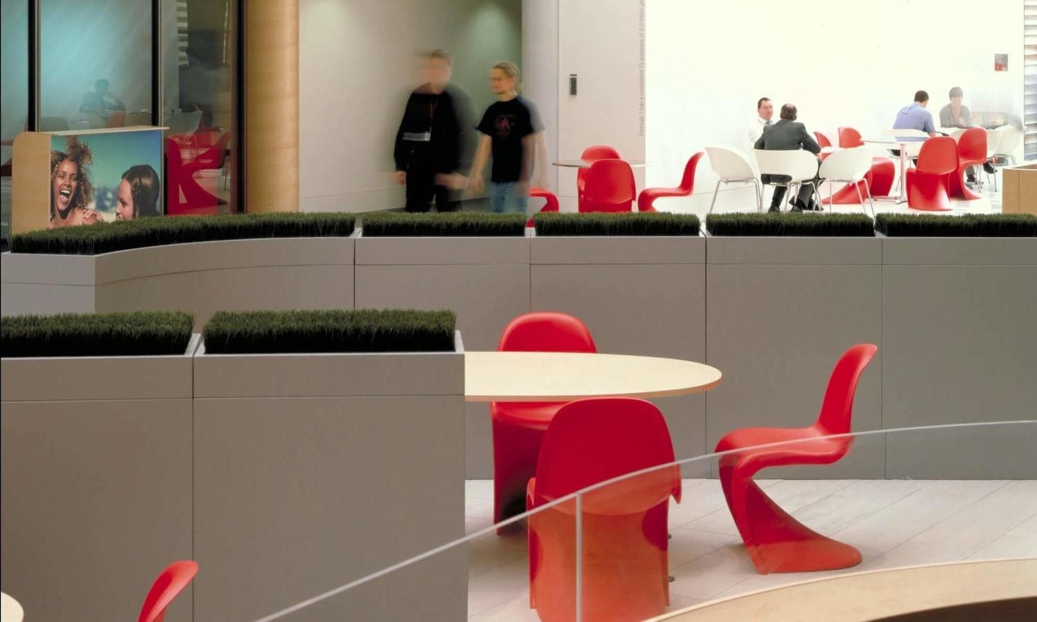 Vodafone: Café seating with red chairs and white tables behind low planters