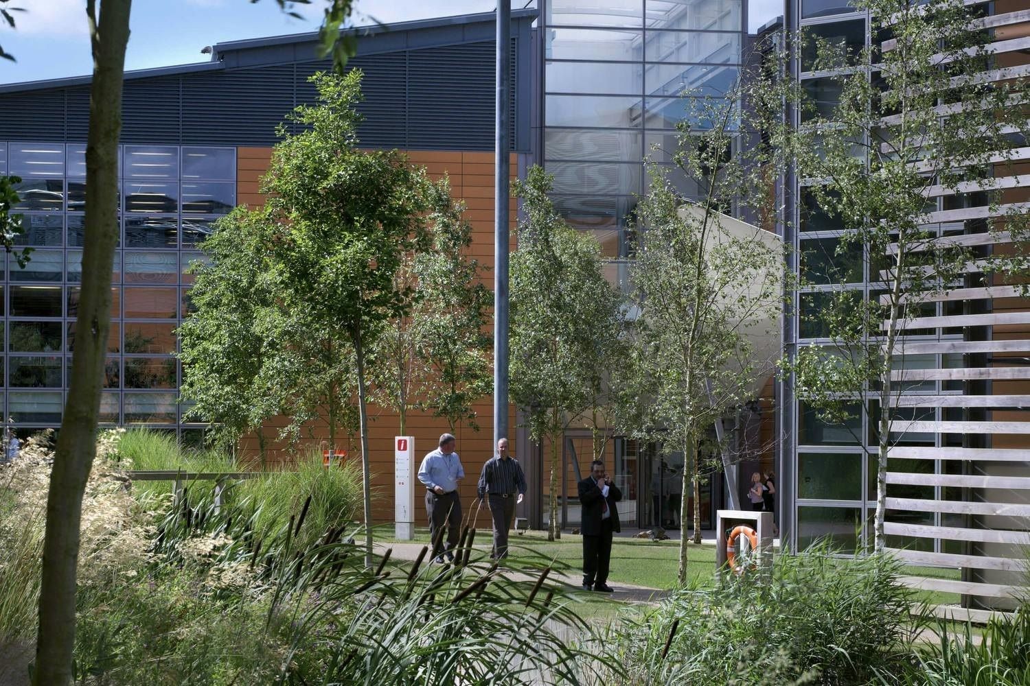 Vodafone: Courtyard planted with trees between glass and terracotta office blocks, people walking in the distance