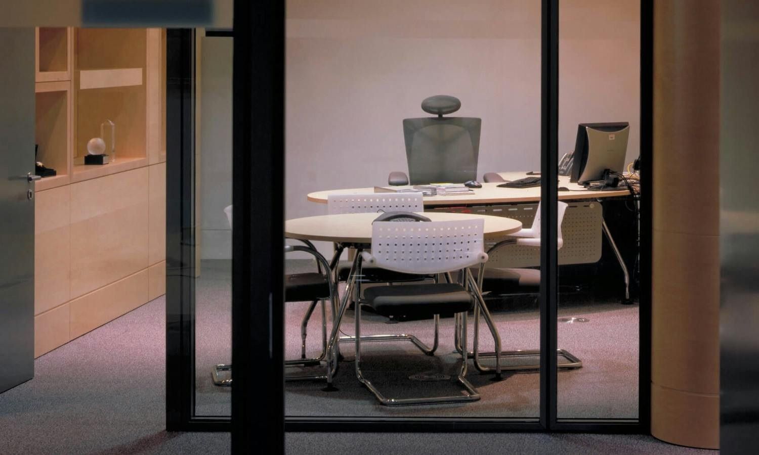 Vodafone: Small glass-walled meeting room with a round table and office chairs