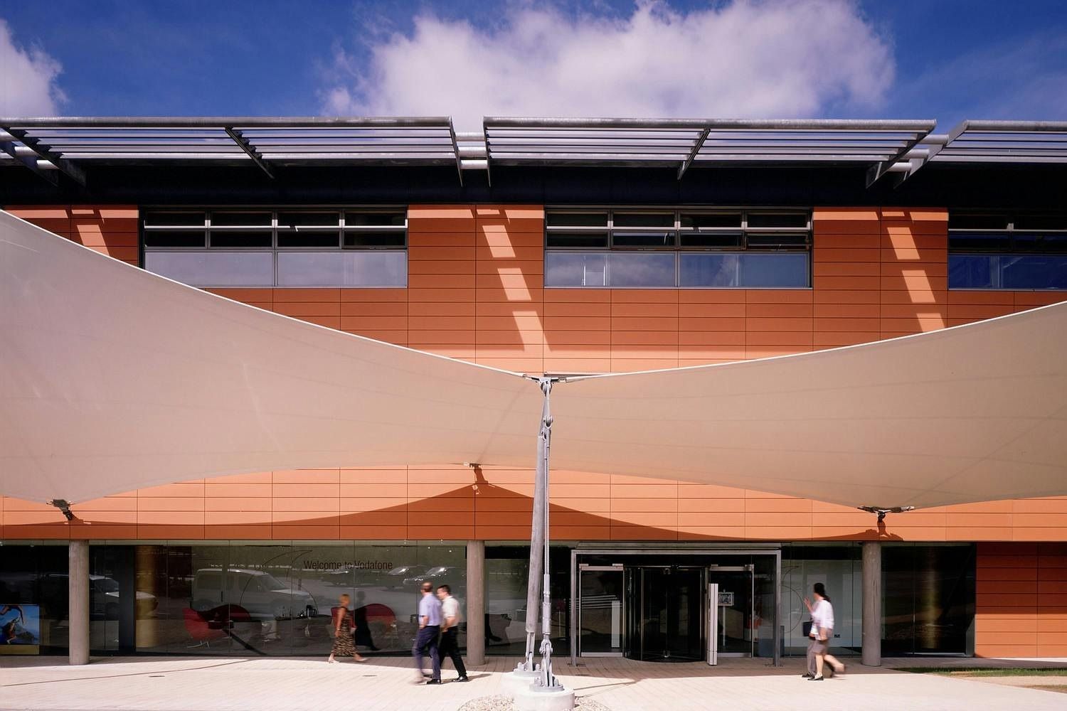 Vodafone: Terracotta-clad office building with a curved white fabric canopy over the entrance