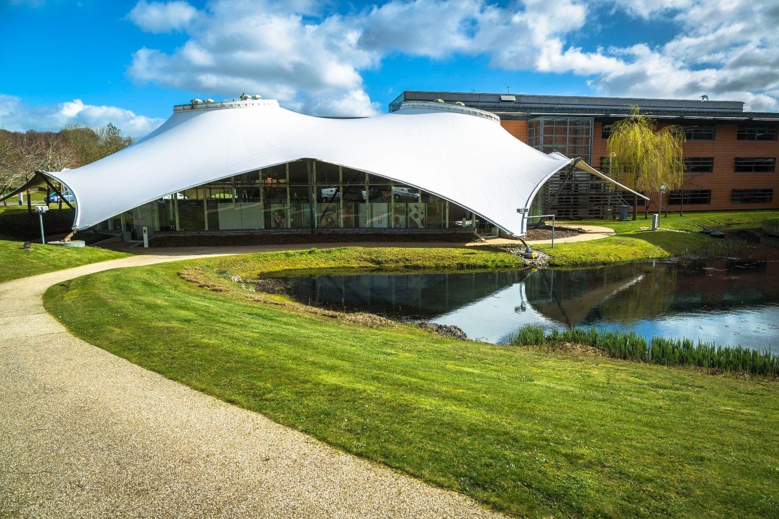 Vodafone: White tensioned-fabric pavilion beside a pond and a curving lawn path