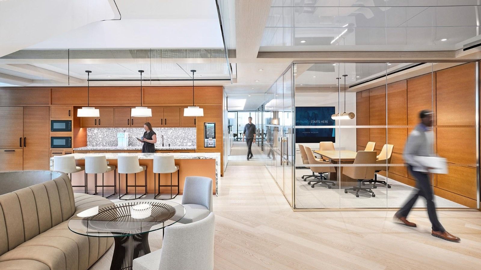 Walker & Dunlop: A kitchen with an island and stools next to a lounge and glass meeting room