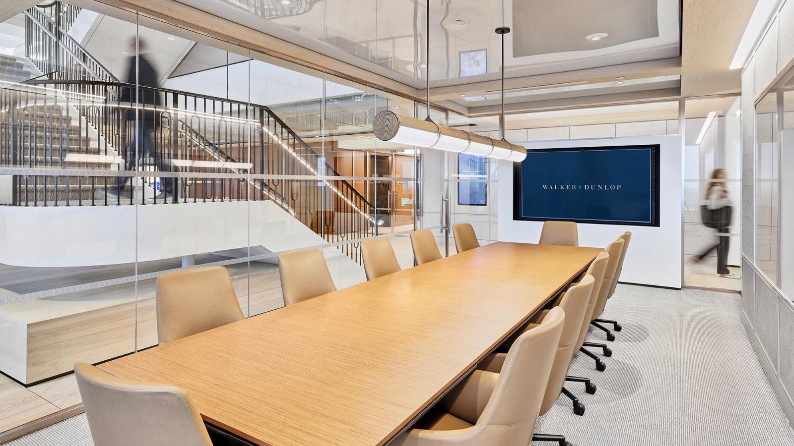 Walker & Dunlop: A long conference table with beige chairs and a screen