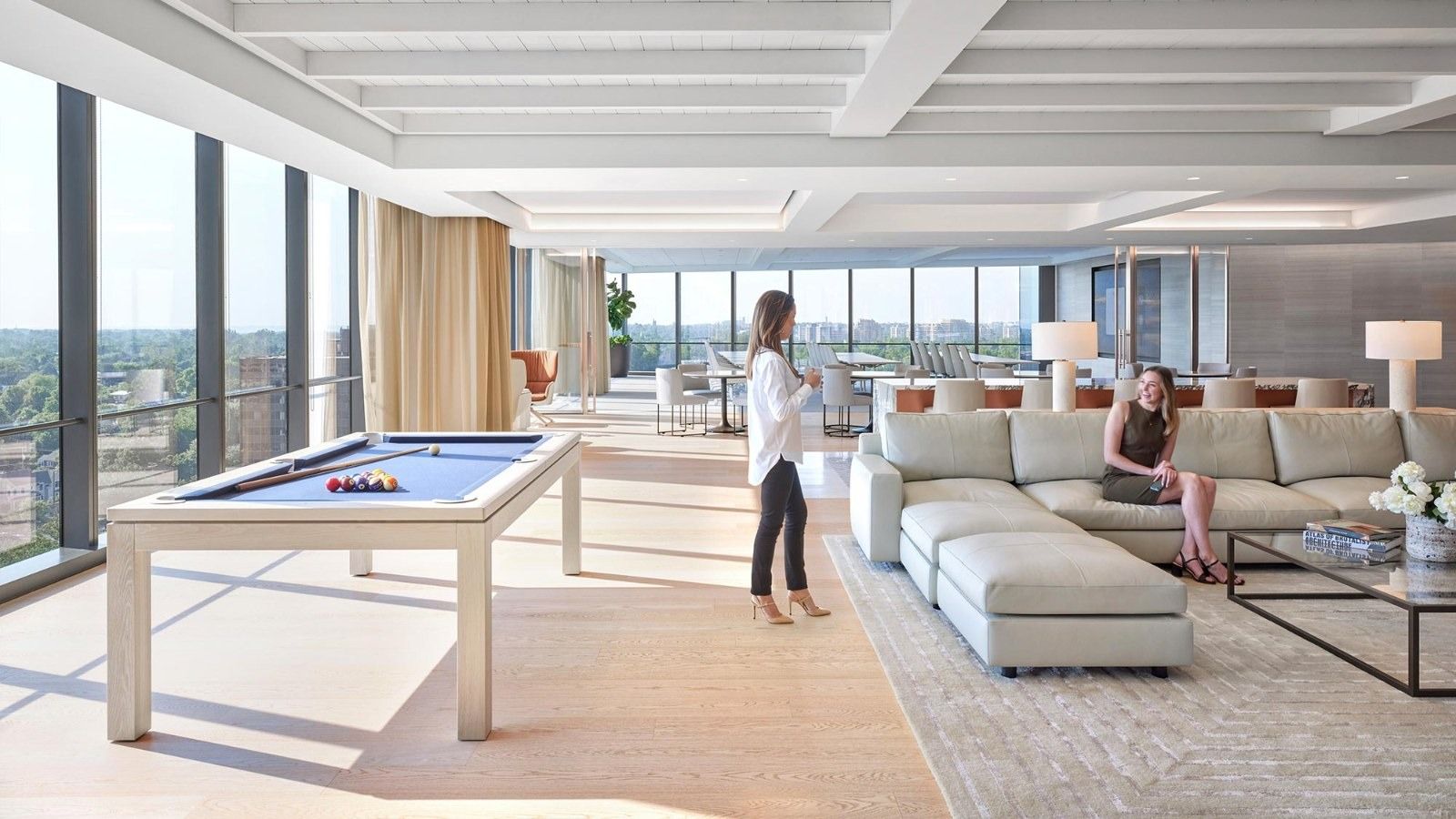Walker & Dunlop: A lounge with a pool table and sectional sofas by tall windows
