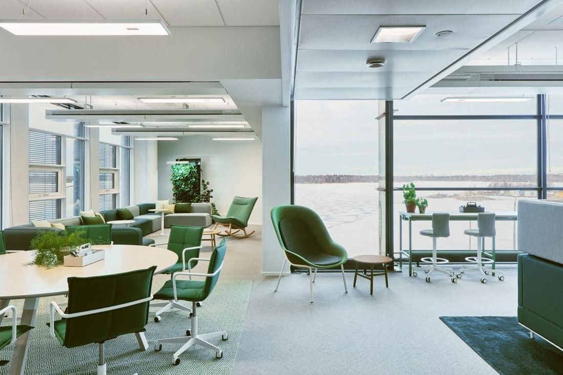 Wärtsilä: Bright open area with green chairs and round tables beside floor-to-ceiling windows looking out on a frozen sea