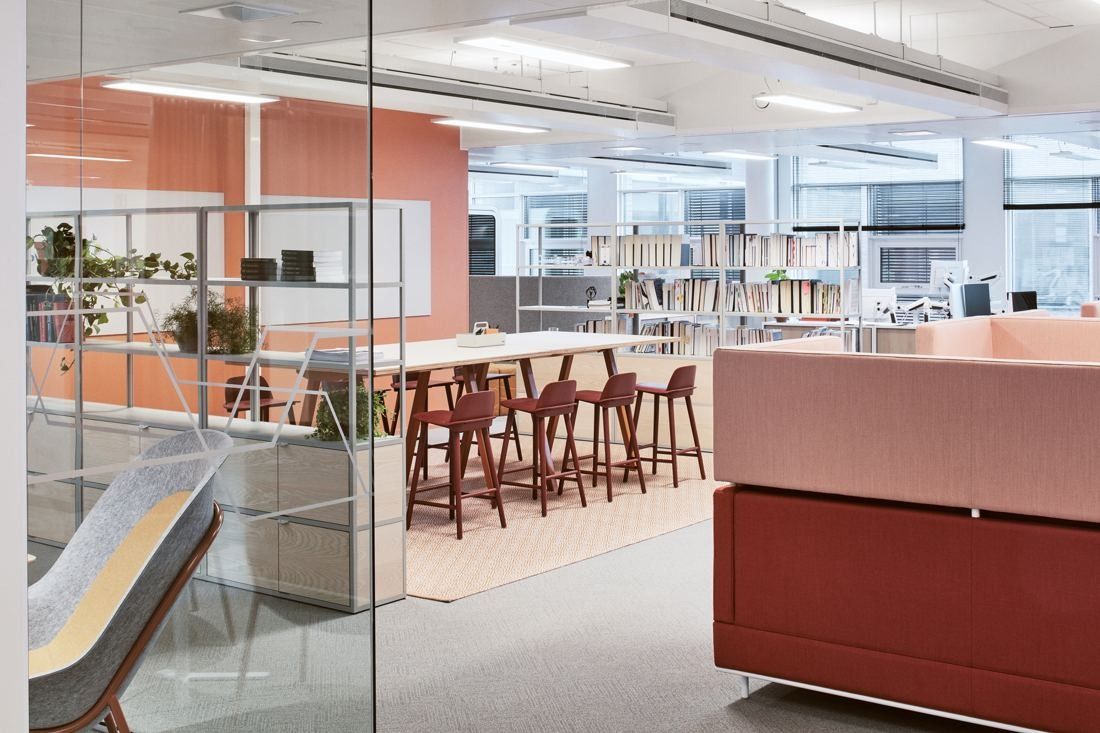 Wärtsilä: Glass-walled area with high tables and red stools beside pink upholstered booths