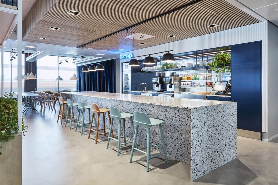 Wärtsilä: Long terrazzo counter with pale green bar stools in an open café, large windows behind