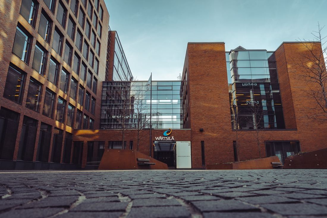 Red-brick and glass office buildings around a cobbled courtyard under a cloudy sky