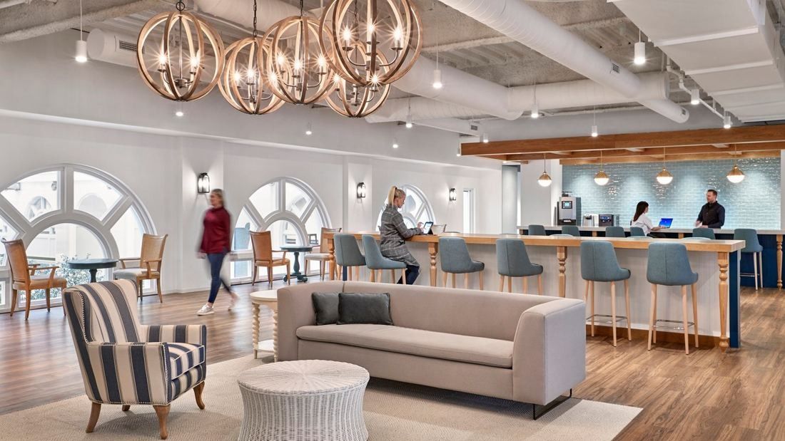Wayfair: Café with orb chandeliers, arched windows, a sofa and striped armchairs and a long bar counter