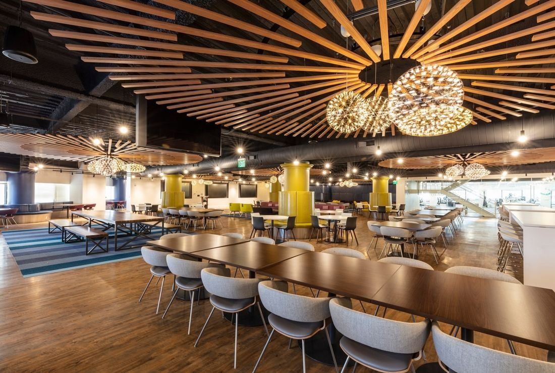 Wayfair: Large dining hall with long tables, white chairs and a radial wooden slat ceiling with globe lights