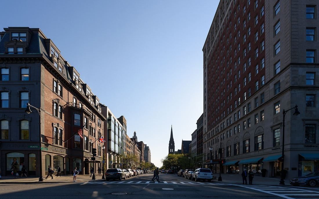 Newbury Street lined with brick and brownstone buildings, looking west with a church spire in the distance