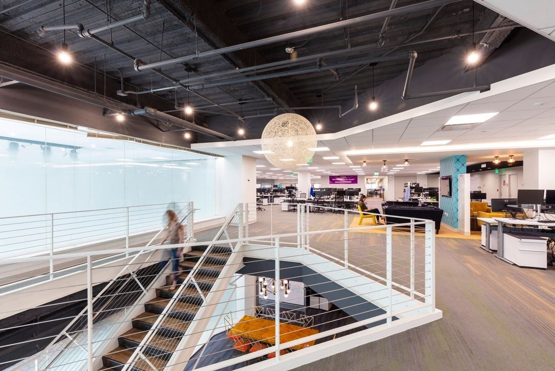 Wayfair: Open stair with white railings cut through the floor, with desks on the level around it