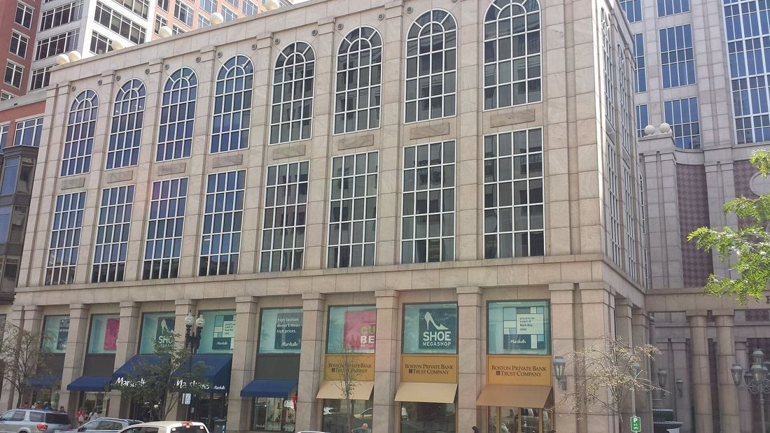 Wayfair: Side wing of the stone office building with tall arched windows and shops at street level