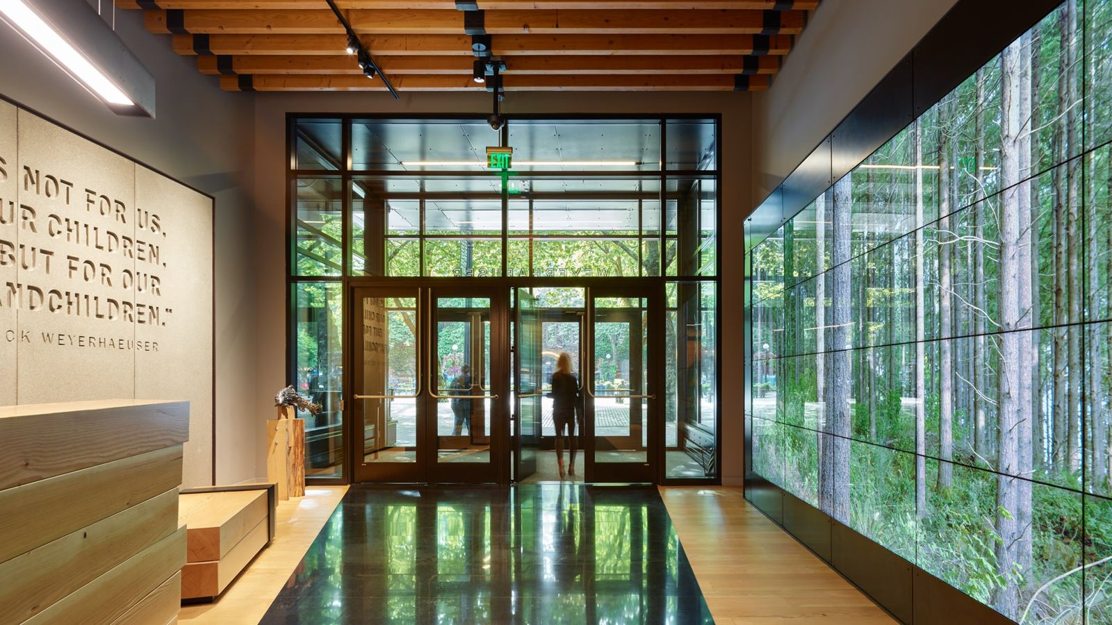 Weyerhaeuser: Wood-lined entry with a tall video wall of forest