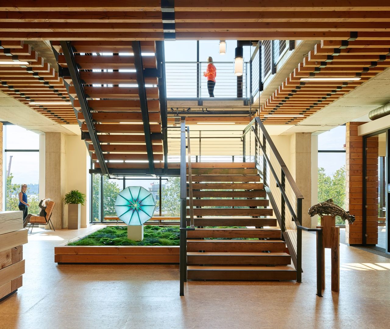 Weyerhaeuser: Wooden stair rising through a double-height space with a planter