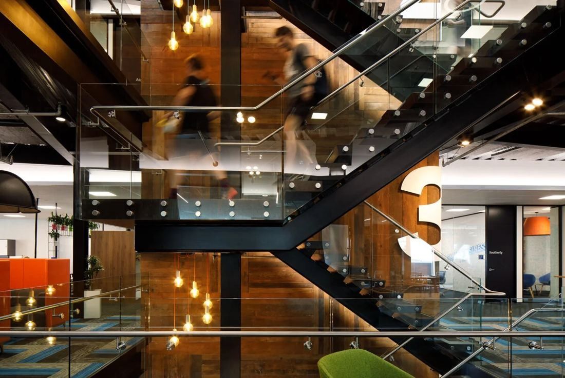 Xero: Black steel stair with glass balustrades and reclaimed timber walls, pendant bulbs and a large number 3 on the landing
