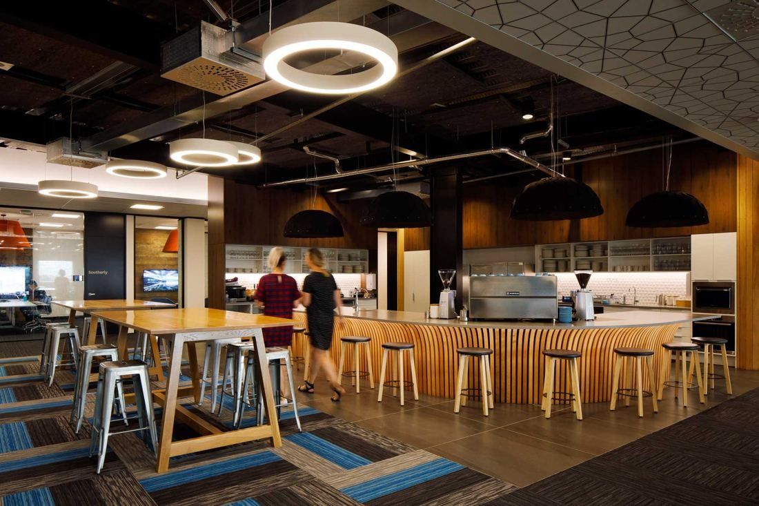 Xero: Cafe area with a curved timber-slat counter, coffee machine, high tables and stools under ring lights