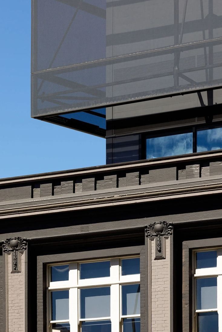 Xero: Close-up of the old cornice and windows below a projecting glass and mesh box
