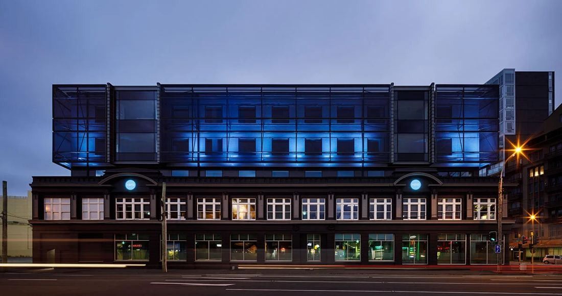 Xero: Frontal view at dusk of the heritage facade with the upper floors glowing blue