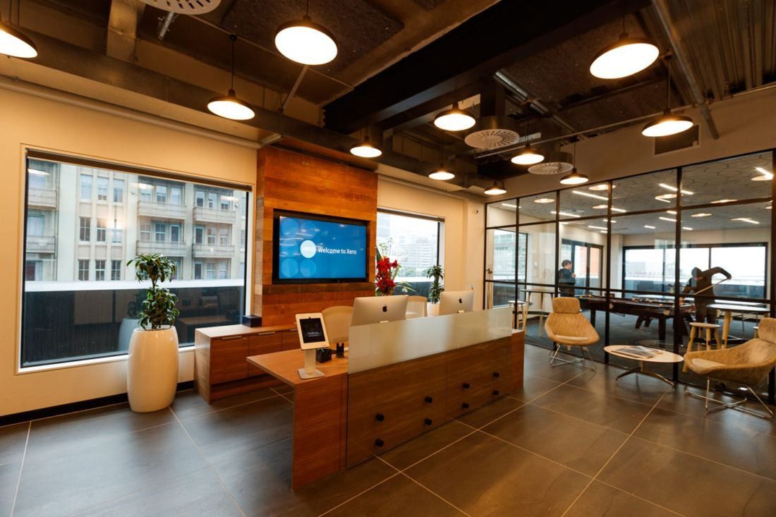 Xero: Reception area with a timber desk, wall screen and glazed meeting rooms
