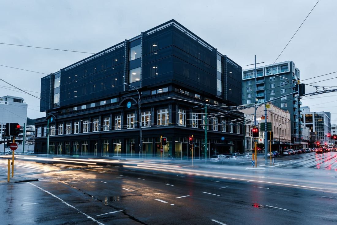 Xero: The building on a wet street corner with traffic light trails in the foreground