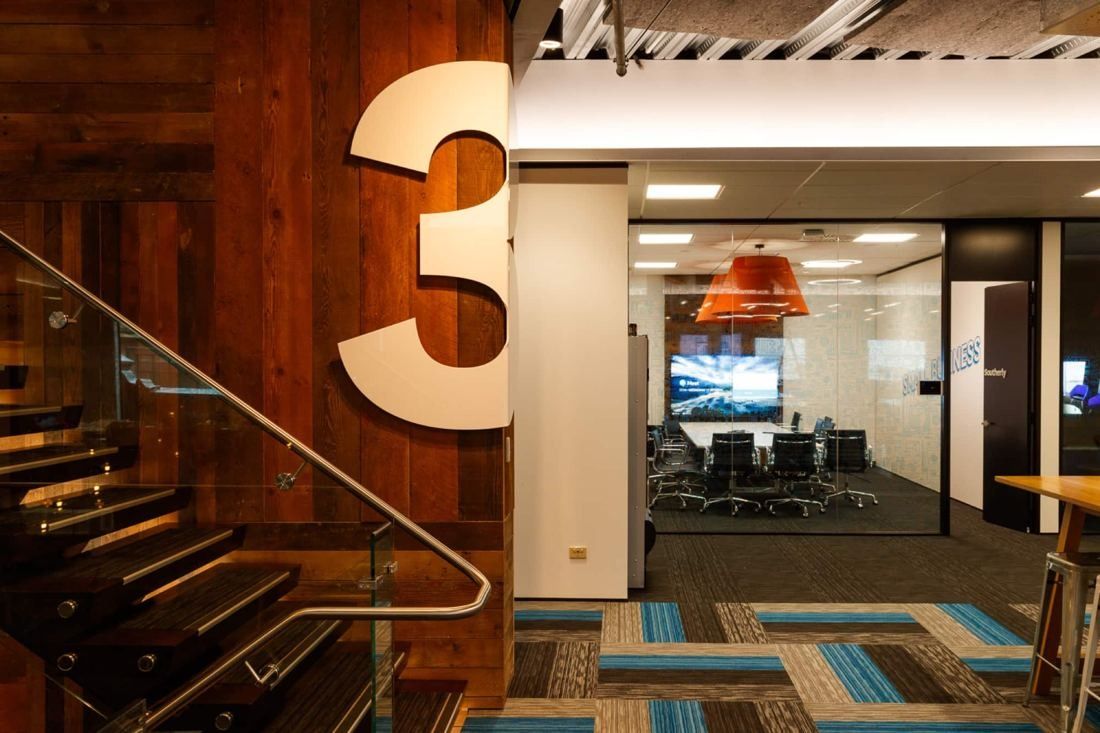 Xero: Timber-clad stair with a large number 3 beside a glass-walled meeting room