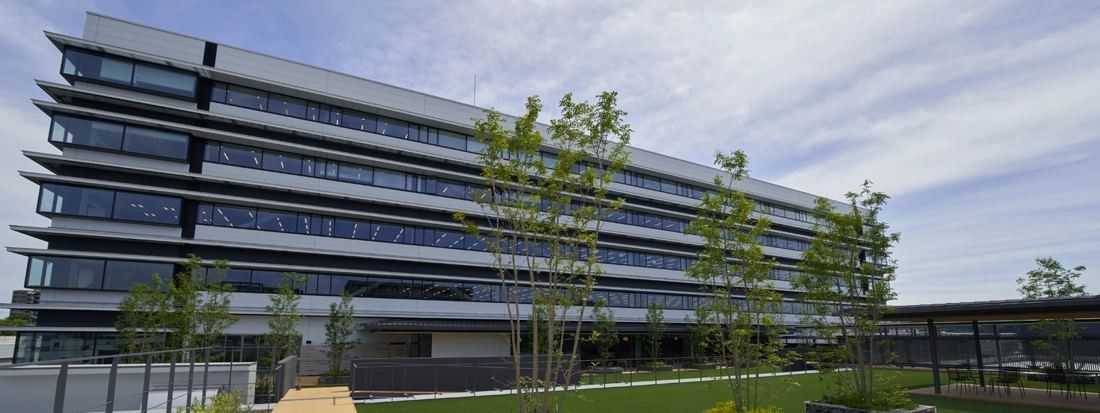 Yamaha: A long, low office building with horizontal bands of windows beside a lawn planted with young trees
