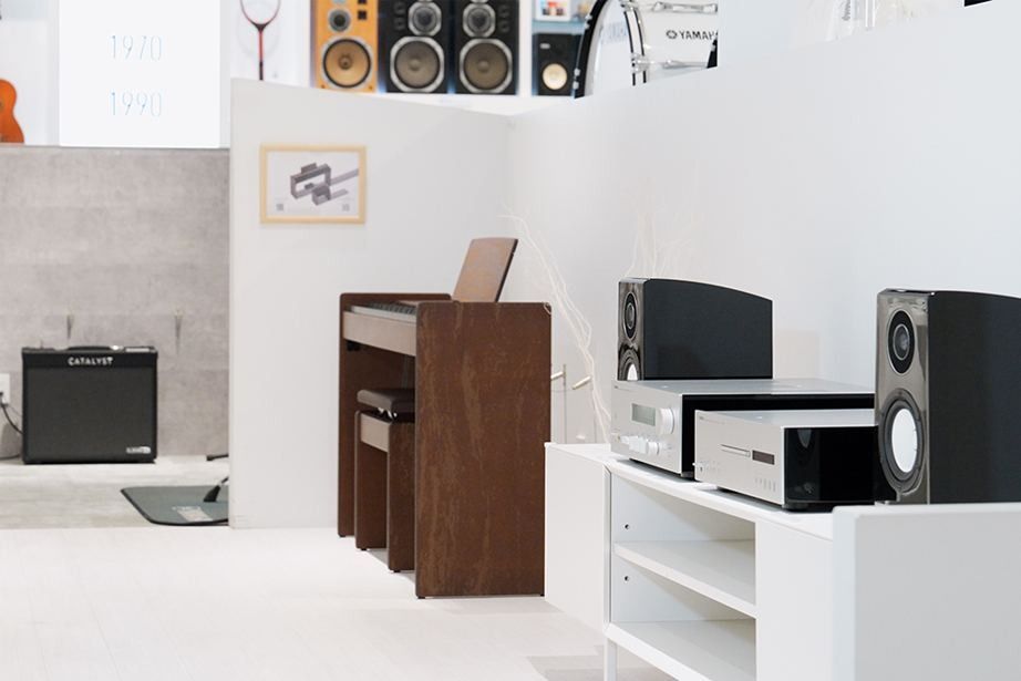 Yamaha: A white gallery corner with a digital piano, guitar amplifier and audio components