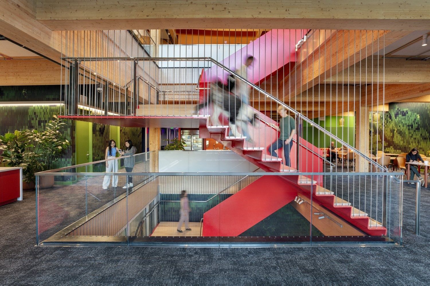 YouTube: Red steel stair rising through a timber-framed atrium with hanging plants