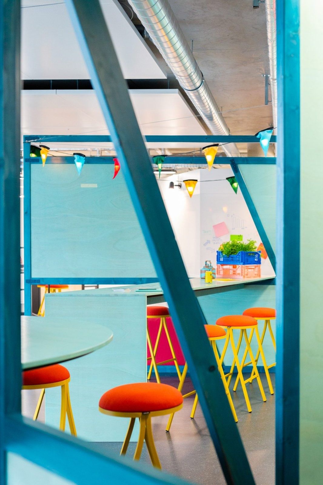 Zalando: Blue steel frame with orange stools and a light blue wall
